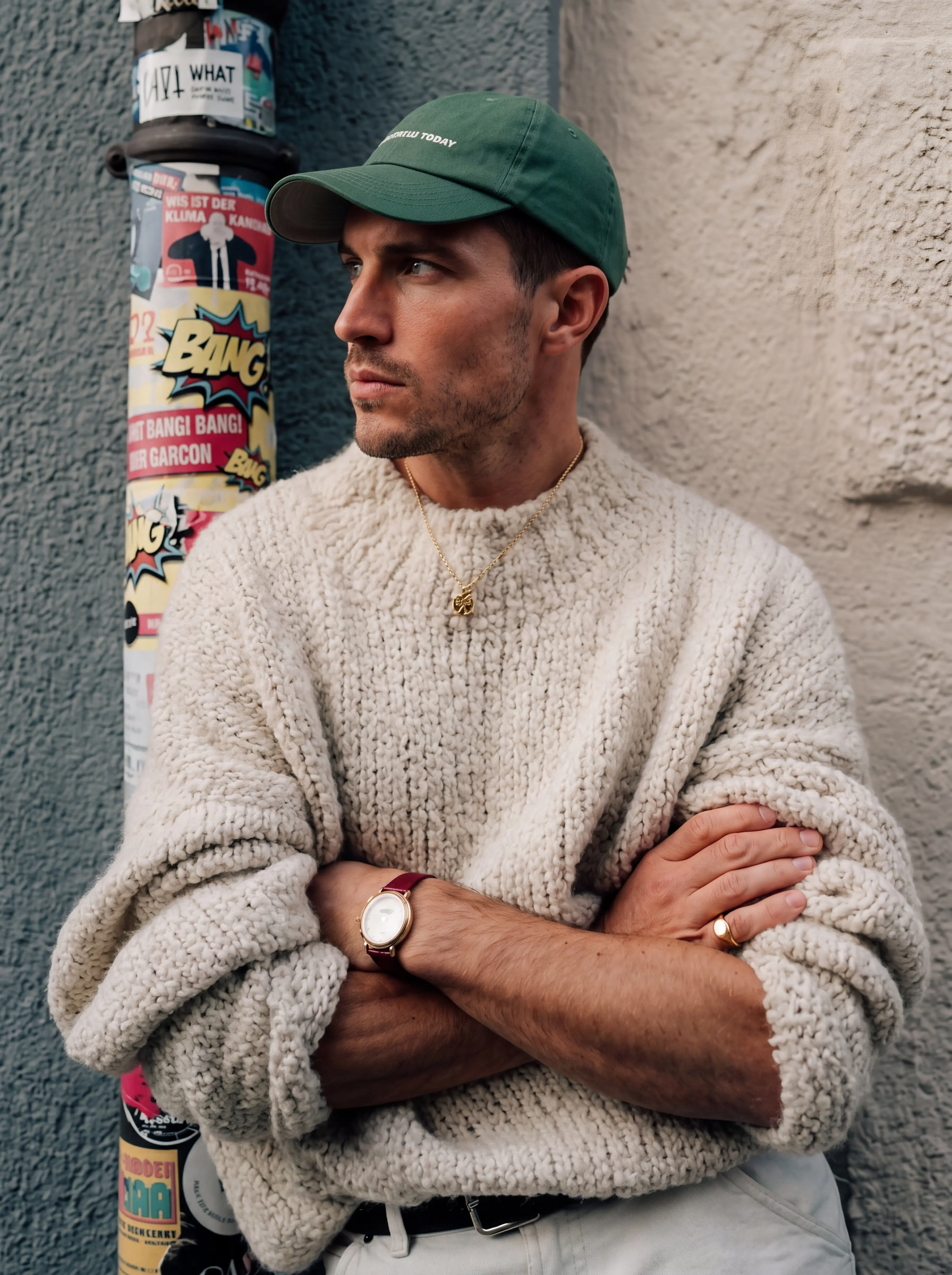 Man in cream knit sweater and green cap on urban street — AI streetwear photography for ecommerce