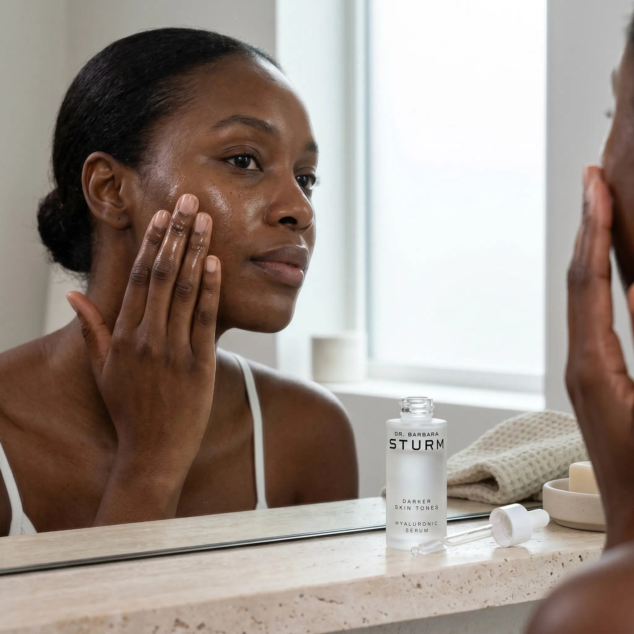Woman applying serum at bathroom mirror with skincare bottle — AI skincare lifestyle photography for ecommerce