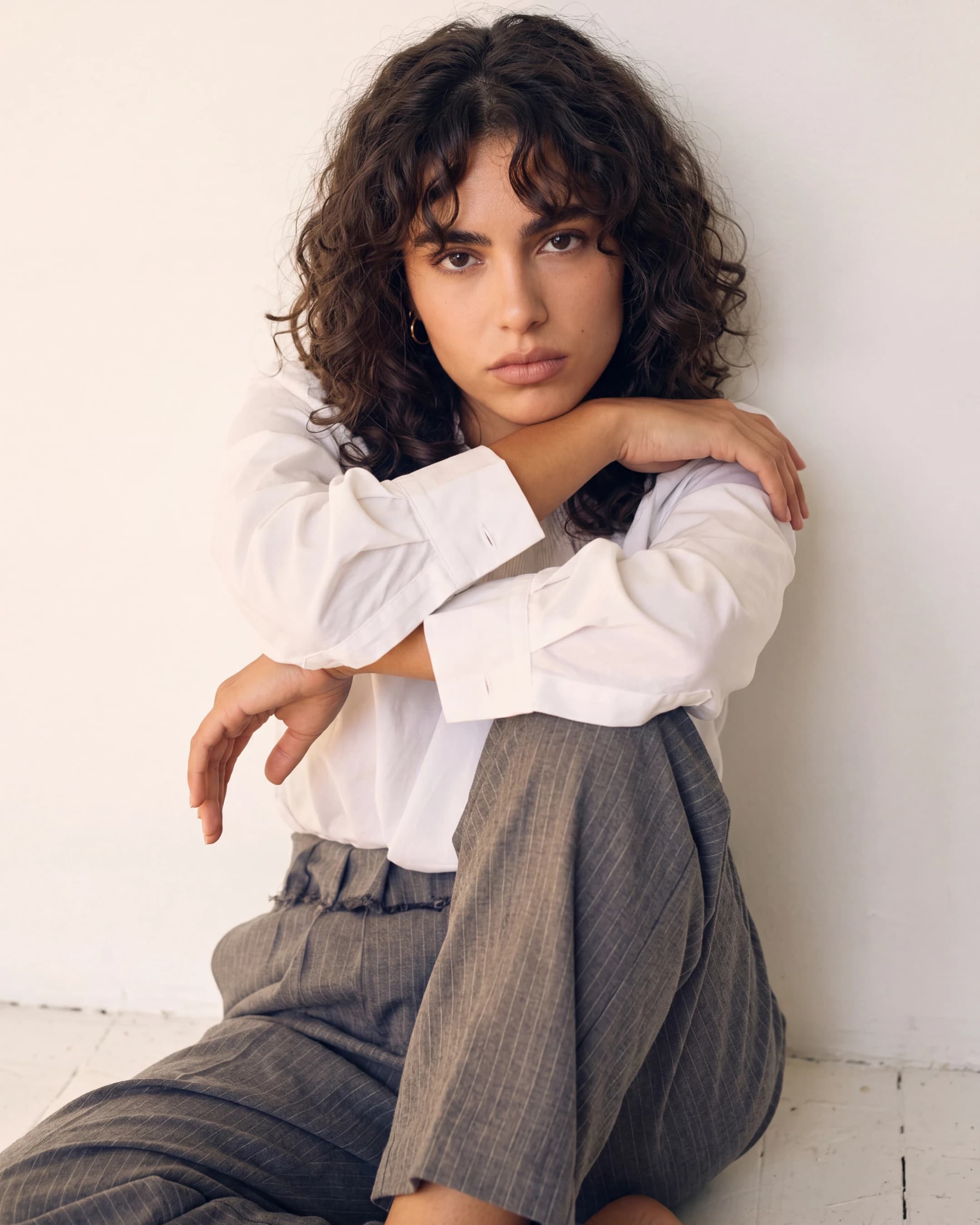 Woman in white shirt and grey trousers seated — AI apparel product photography for ecommerce lookbooks