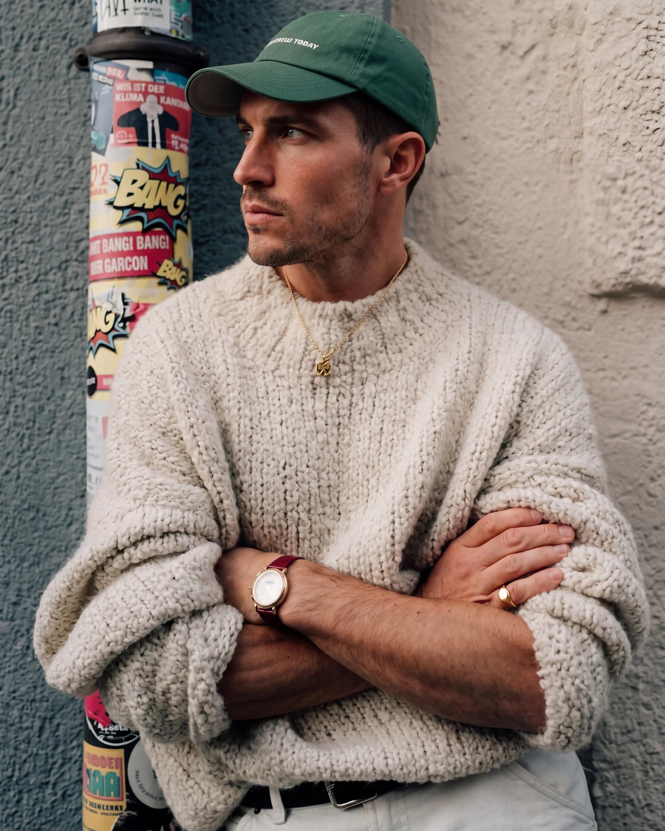 Man in cream knit sweater and green cap — AI menswear lifestyle product photography for ecommerce