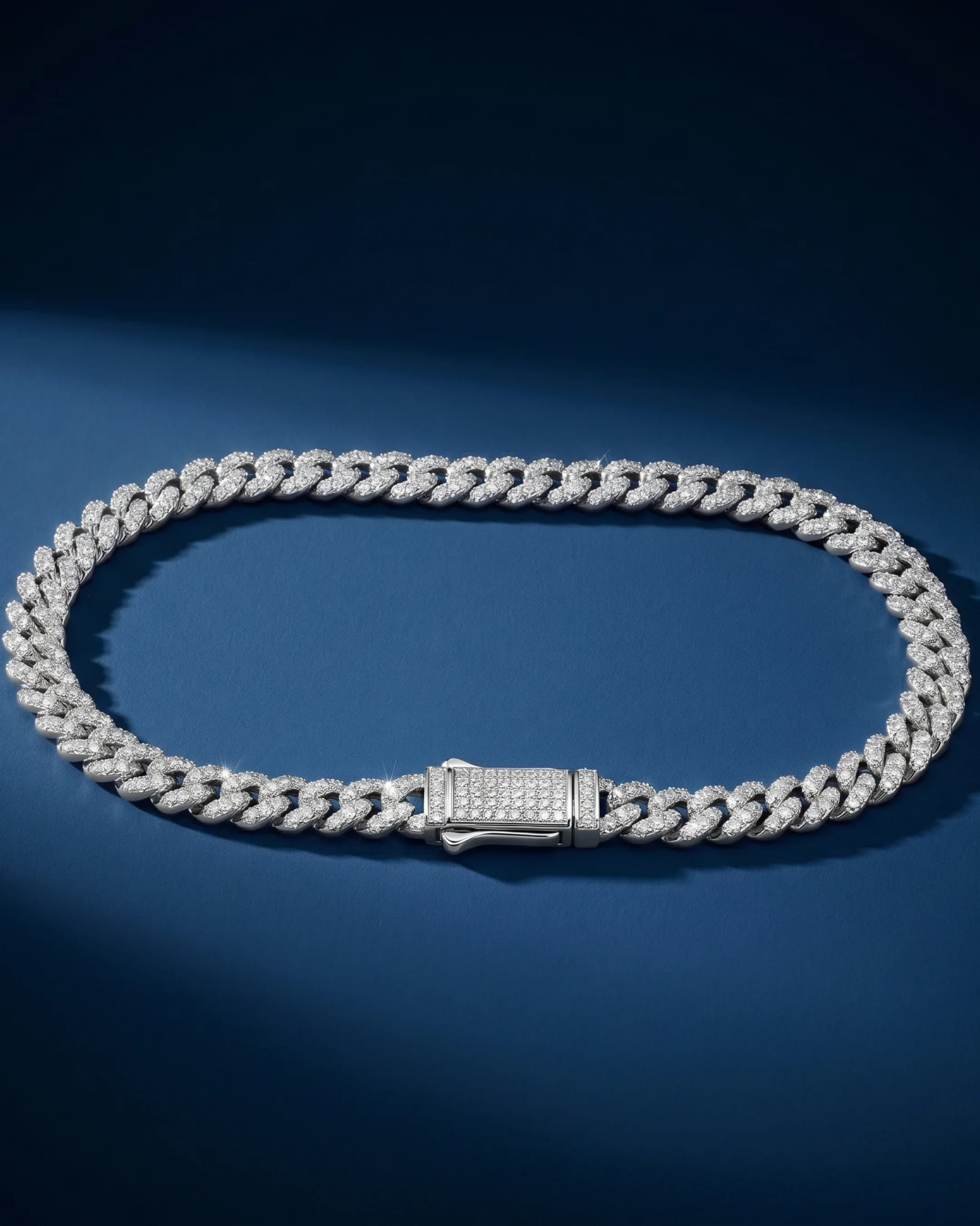 Silver pavé cuban-link chain on blue backdrop — AI jewelry product photography for ecommerce listings