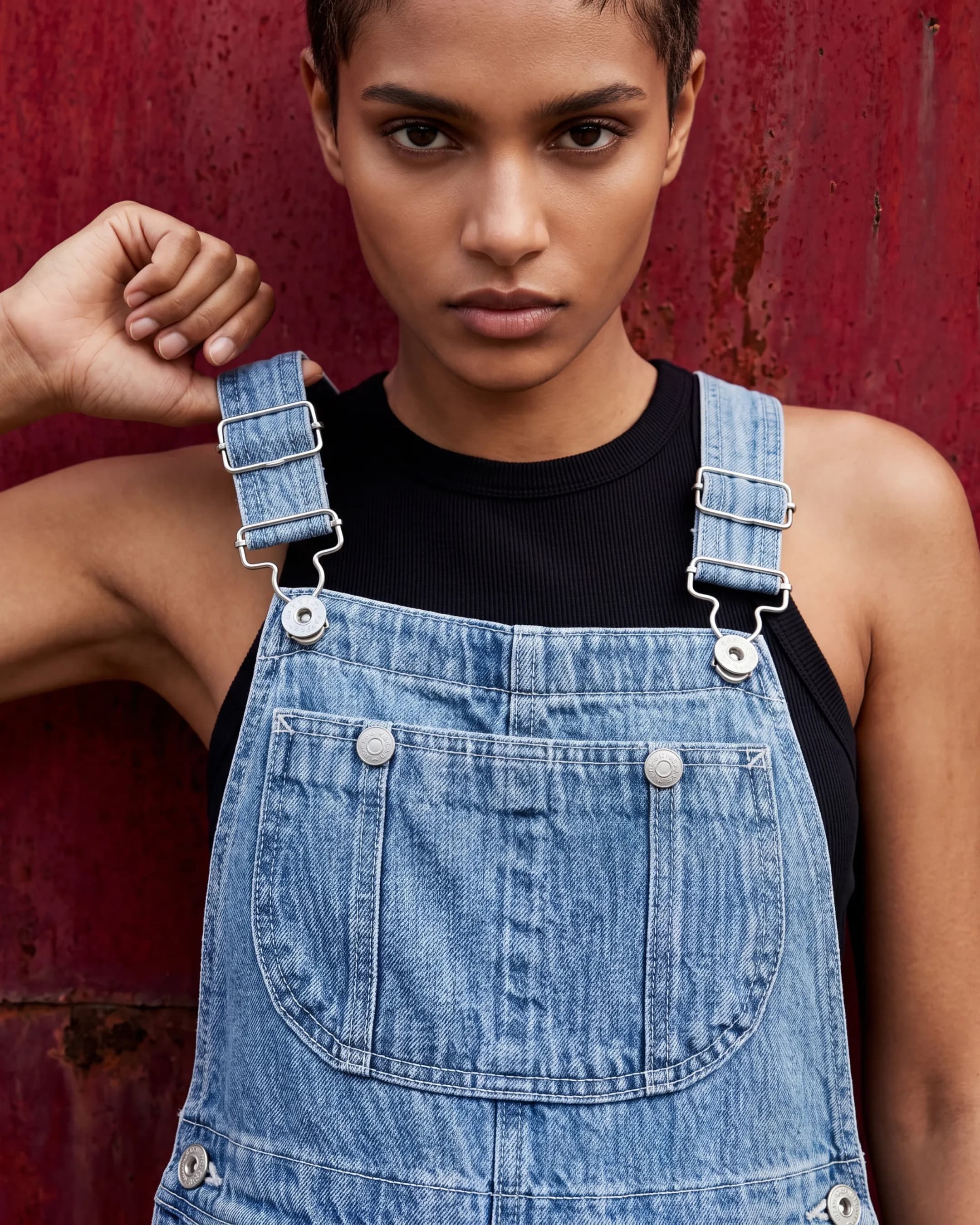 Woman in blue denim overalls on red backdrop — AI apparel product photography for ecommerce PDPs
