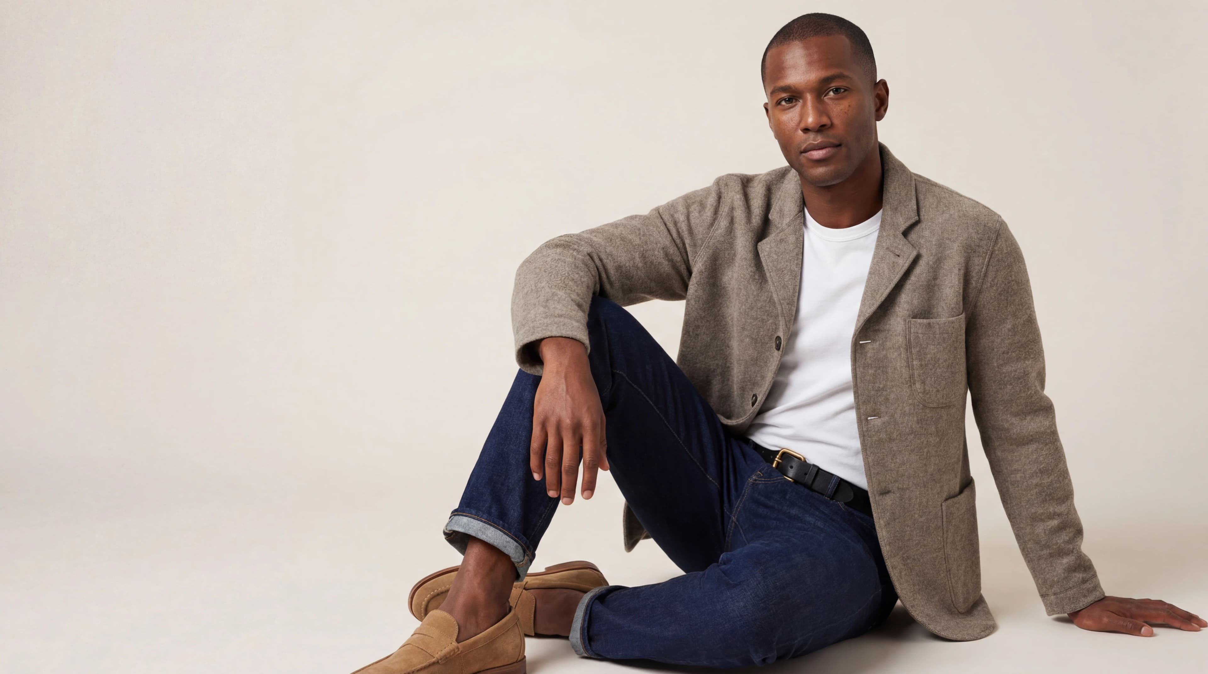 Man in linen blazer and jeans seated casually — AI menswear product photography for ecommerce lookbooks